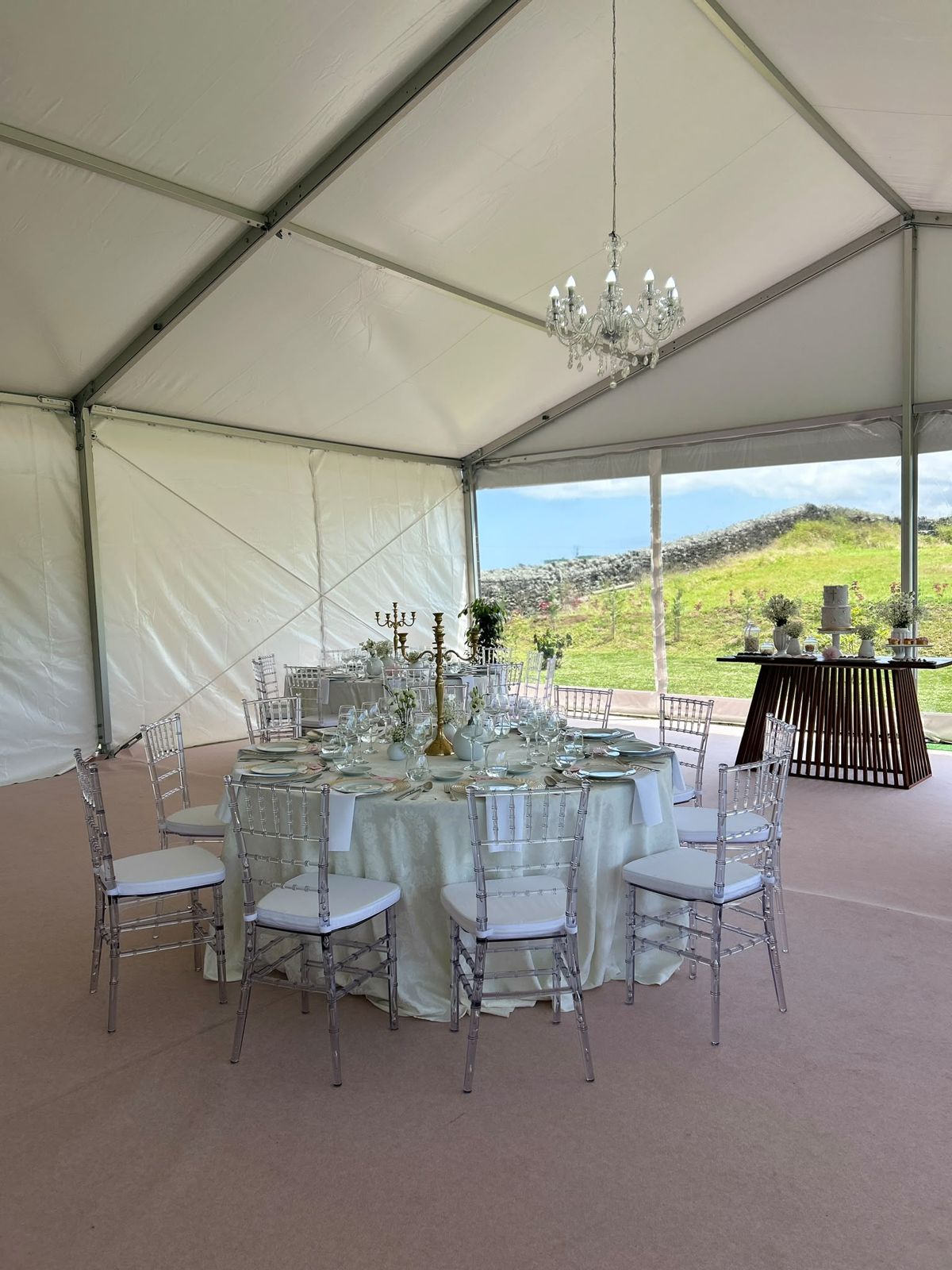Mesa redonda posta sob um candelabro de cristal, com vista para os campos